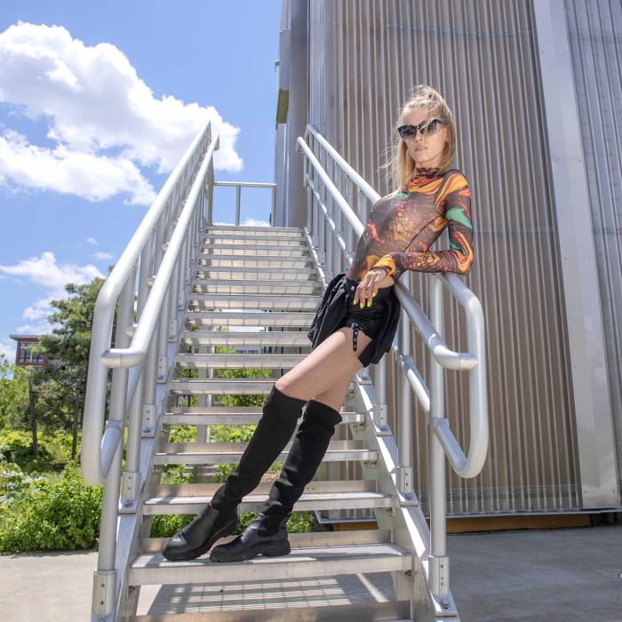 Caucasian female model on metal steps in streetwear photographed by Marty Gottlieb